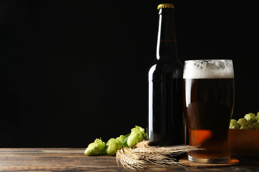 Beer, wheat and hop on wooden table