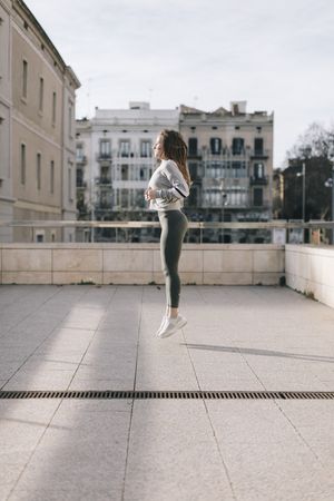Side view of young woman jumping on a rooftop