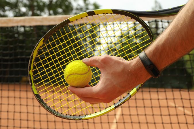 Man hold racket and tennis ball, close up