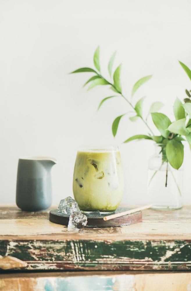 Iced matcha drink with creamer on side, with eco friendly straw and leaves