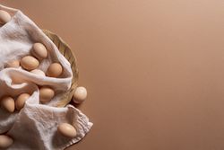 Brown eggs on wooden plate on brown background