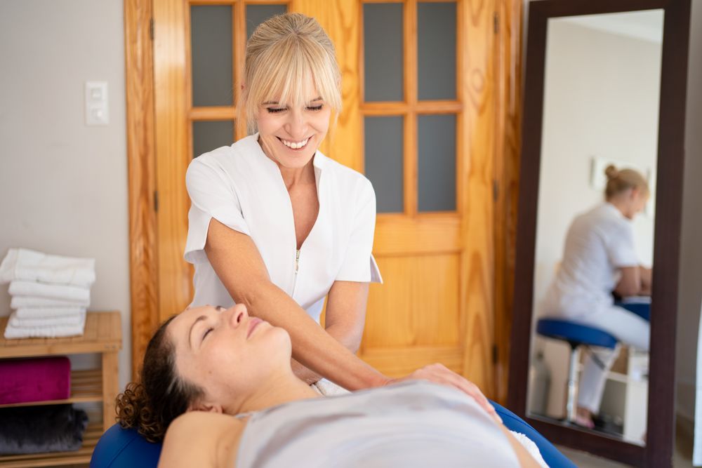 Female massage therapist smiling with client