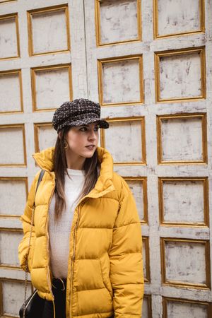 Stylish woman in yellow near shabby wall on street