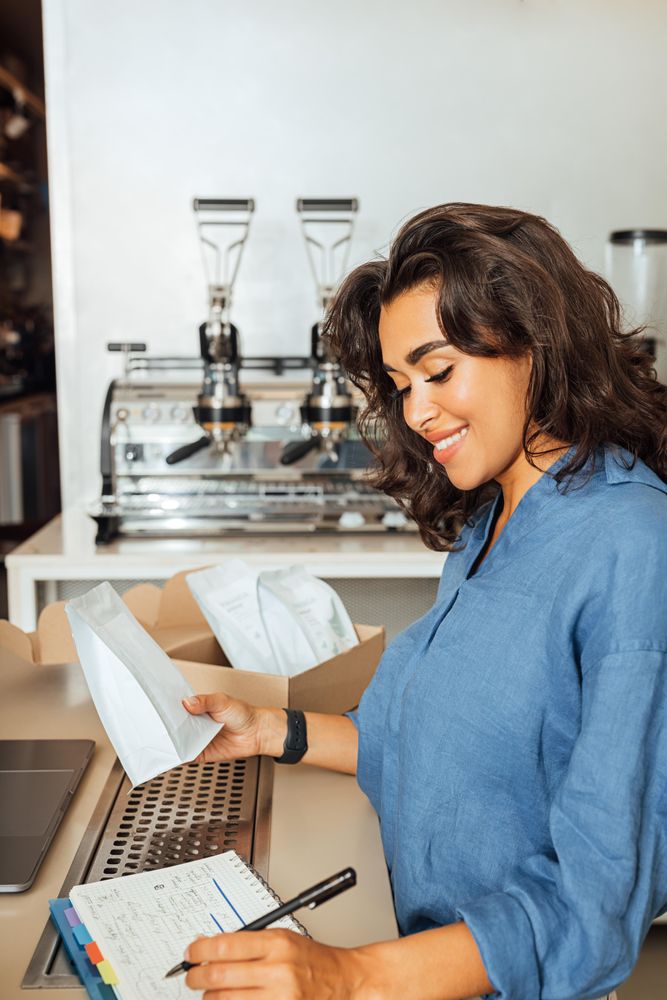 Woman checking calendar in coffee shop while holding bag of beans