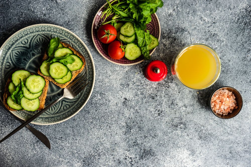 Top view of lunch of bread with cucumber slices, tomatoes and Himalayan salt