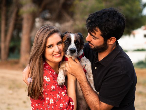 Happy couple with friendly cute dog outdoors
