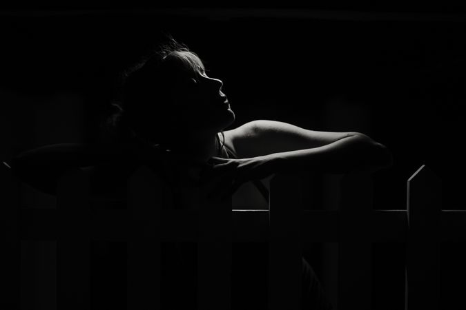 Silhouette of sensual woman leaning in shadow