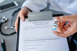 Female doctor's hand showing coronavirus vaccine vial
