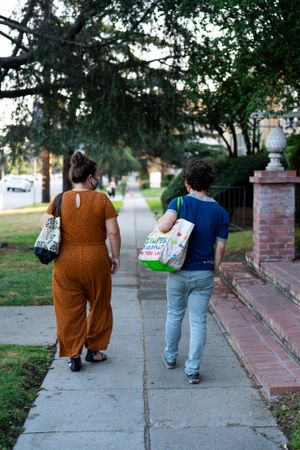 Back view of man and woman walking down city street carrying grocery bags