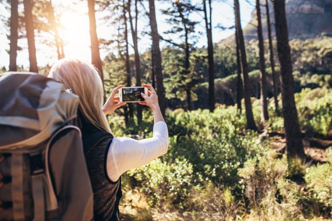 Female taking photograph using a mobile phone during trekking