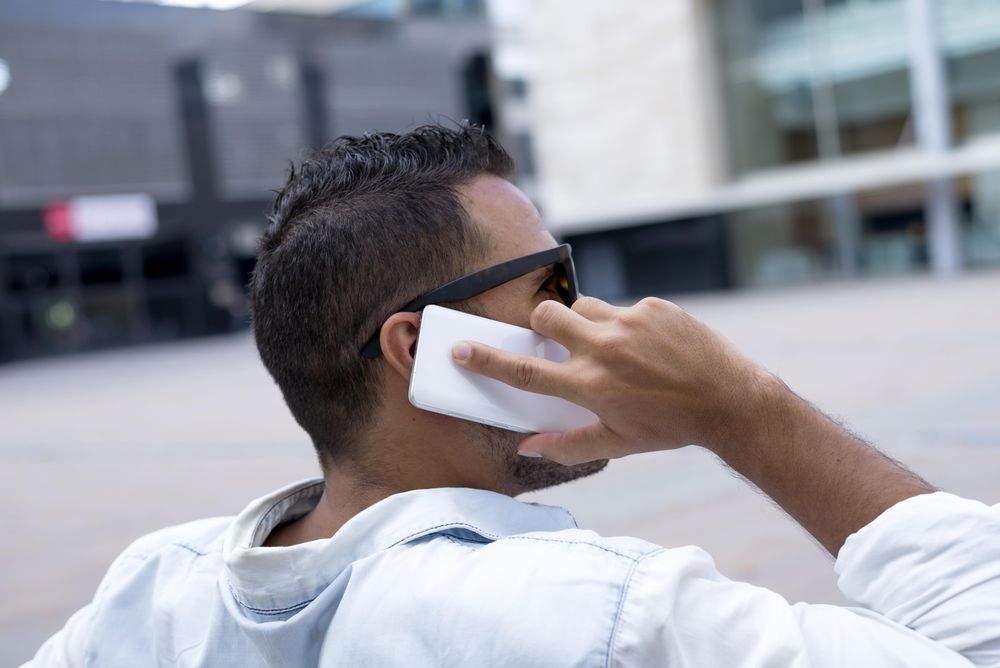 Back of male sitting on bench speaking on phone