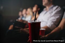 Close up shot of young people with soft drinks in movie theater, focus on cold drink glass 4OjRL5