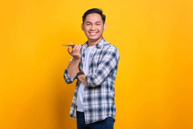 Asian male smiling while using speaker phone in studio shoot