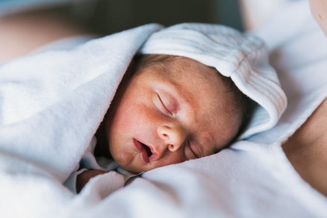 Close up view of a cute newborn baby sleeping on his mother.