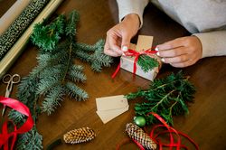 Woman wrapping beautiful Christmas gift at table