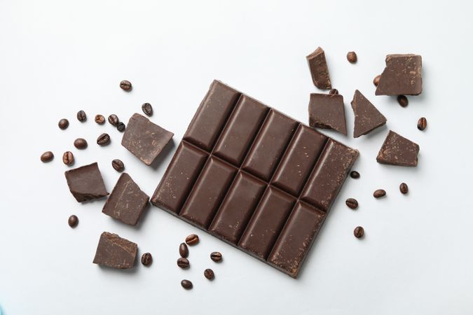 Chocolate bar and coffee seeds on neutral background