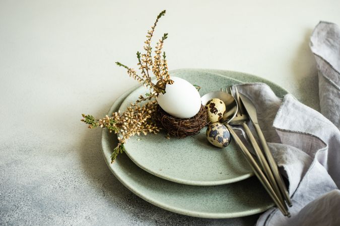 Easter table setting with decorative eggs with nest on ceramic plate
