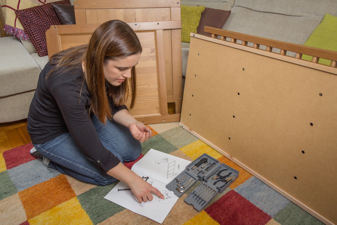 Woman reading instructions to assemble furniture