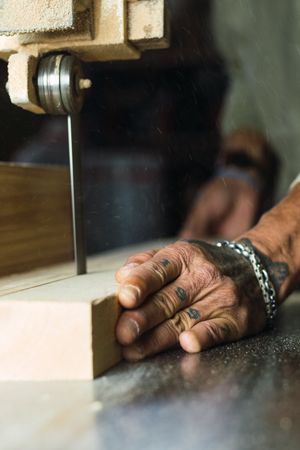 Anonymous male woodworker cutting plank with band saw