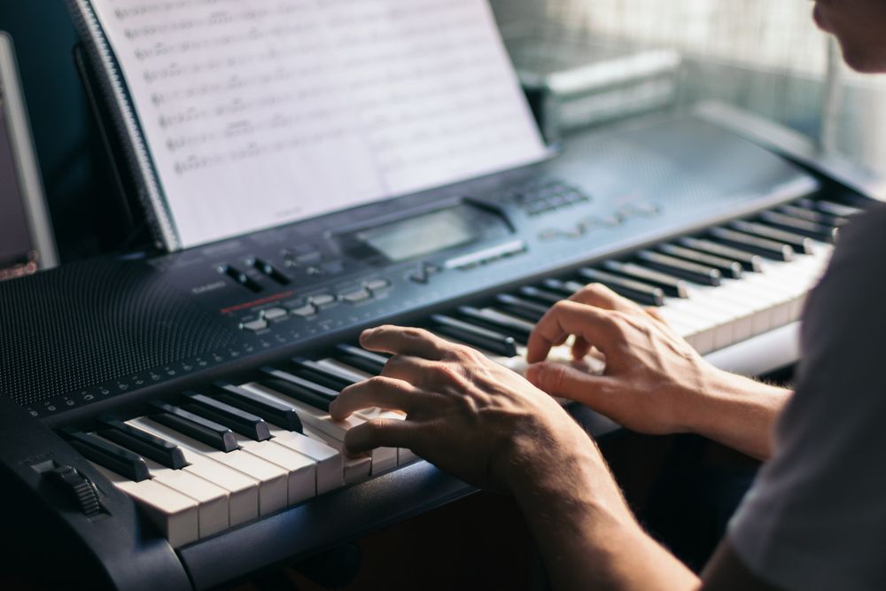man playing piano with a music sheet