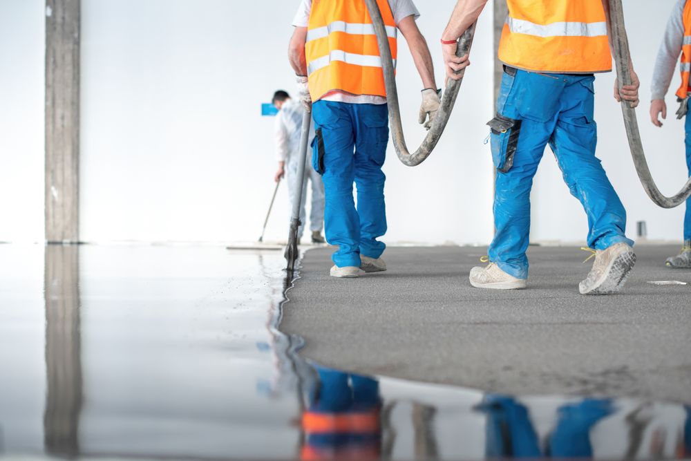 Group of workers pouring concrete floor
