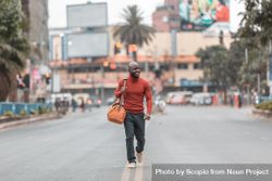 Man in red shirt holding bag walking on street bxMYn0