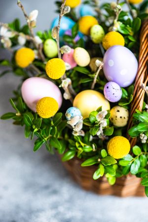 Close up of pastel Easter eggs & leaves in decorative basket