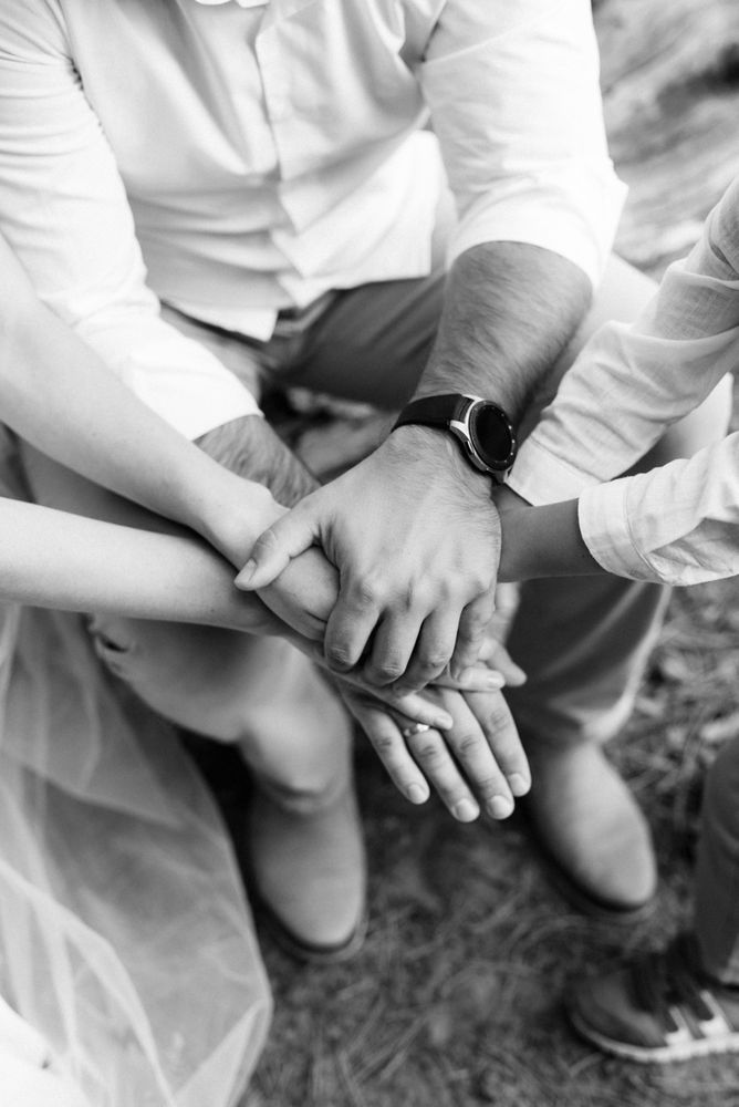 Grayscale photo family piled up hands as team