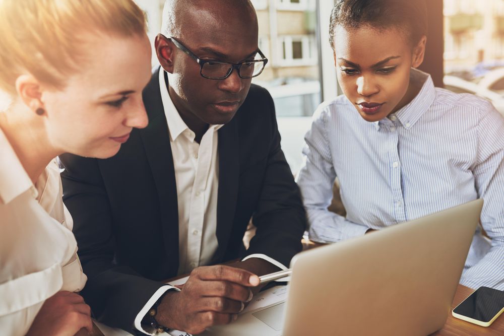 Close up of multi-ethnic group working together around a laptop