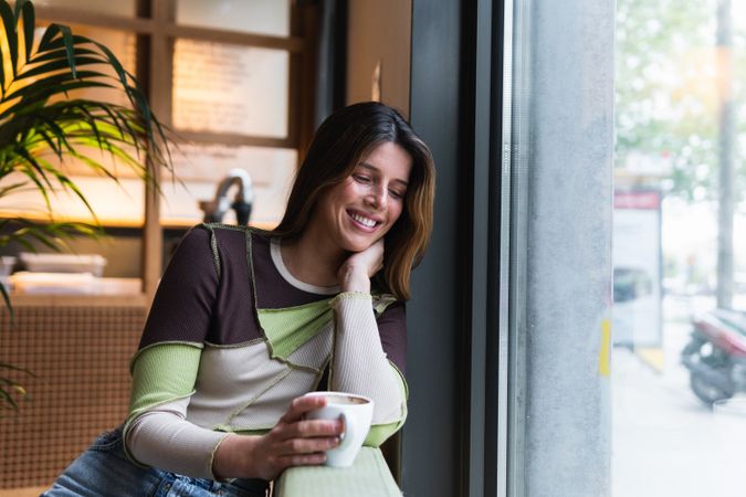 Cheerful woman with cup of coffee in cafe