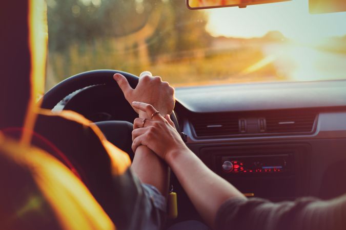 Man and woman holding hands while driving