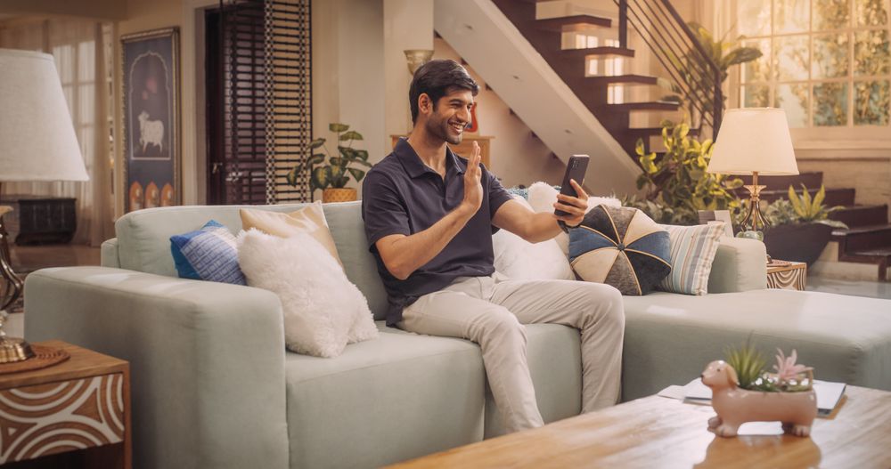 Indian Man Using Smartphone while on Video Call at Home, Doing Remote Work