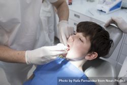 Dentist examining male teenager's teeth in clinic 4MQvG4