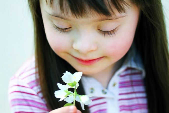 Portrait of young girl with Down syndrome holding a flower in the park
