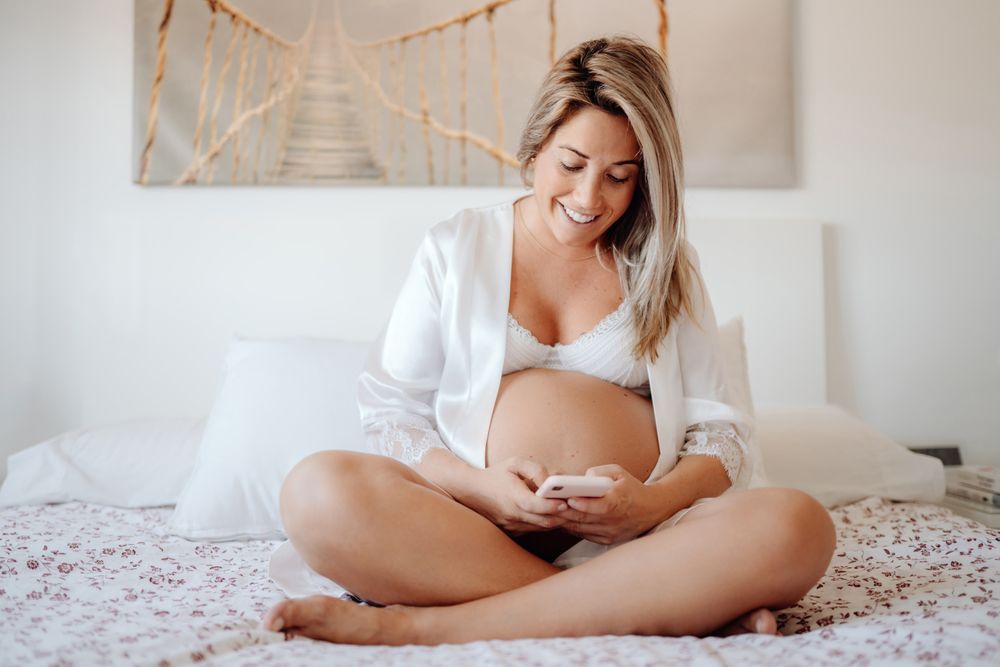 Smiling pregnant woman using smartphone at home