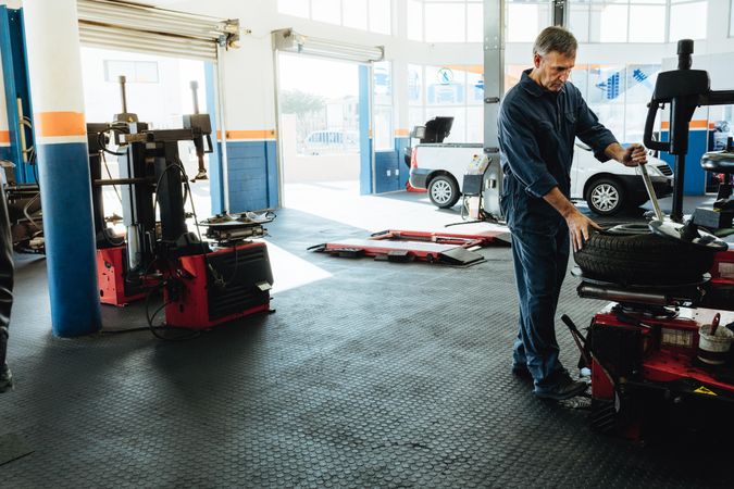 Auto shop with owner working on tire removal machine
