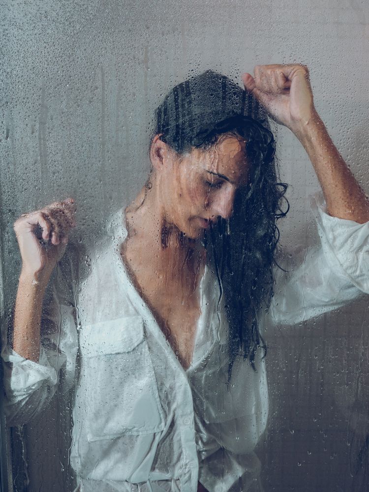 Through glass of woman standing in shower cabin