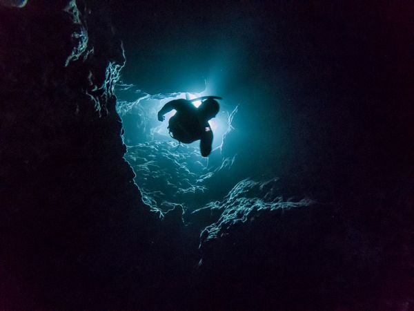 Underwater shot of person diving in cave