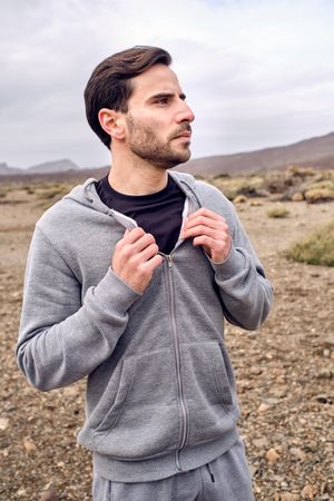 Thoughtful man in hoodie standing on countryside road