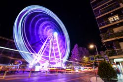 Slow shutter shot of purple lit ferris wheel at night