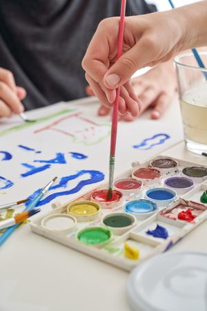Unrecognizable children painting on paper