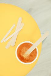 Liquid yellow paste for sugaring on yellow background, top view