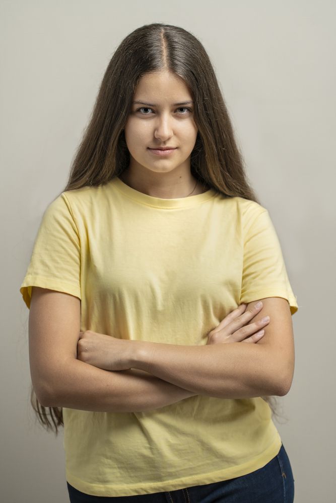 Confident young woman standing with folded arms showing natural skin texture in portrait