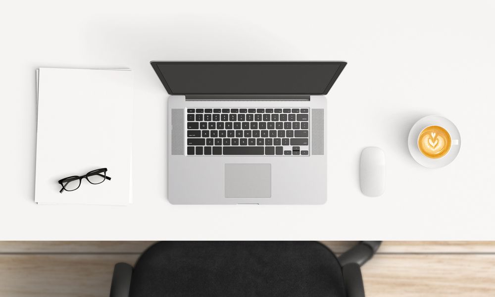 Modern workplace with laptop, coffee cup and notebook copy space on table background. Top view. Flat lay style.