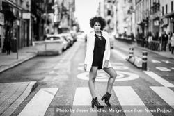 B&W female in short dress and blazer standing in the middle of street 0yZ8G5