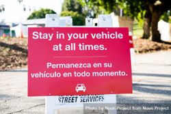 Sign with words “Stay in your vehicle at all times” written in English and Spanish at testing site 0Ld7D0