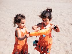 Cute toddler girls playing on sandy beach