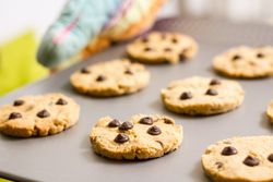 Woman holding a tray with baked cookies with kitchen gloves