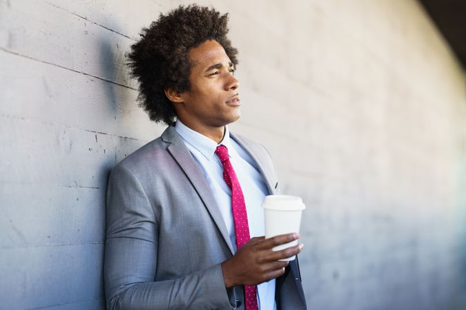 Contemplative man looking in the distance holding a to-go drink