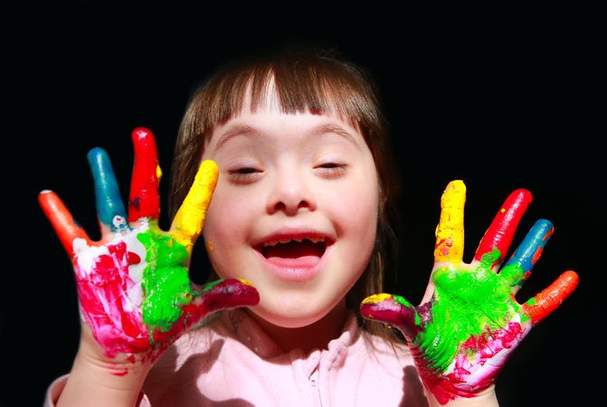 Excited child holding hands out with finger paint on them